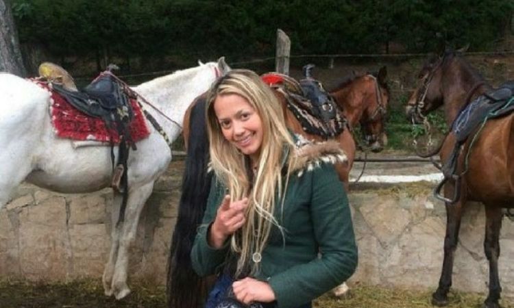 Diana Lasso posing in front of horses.